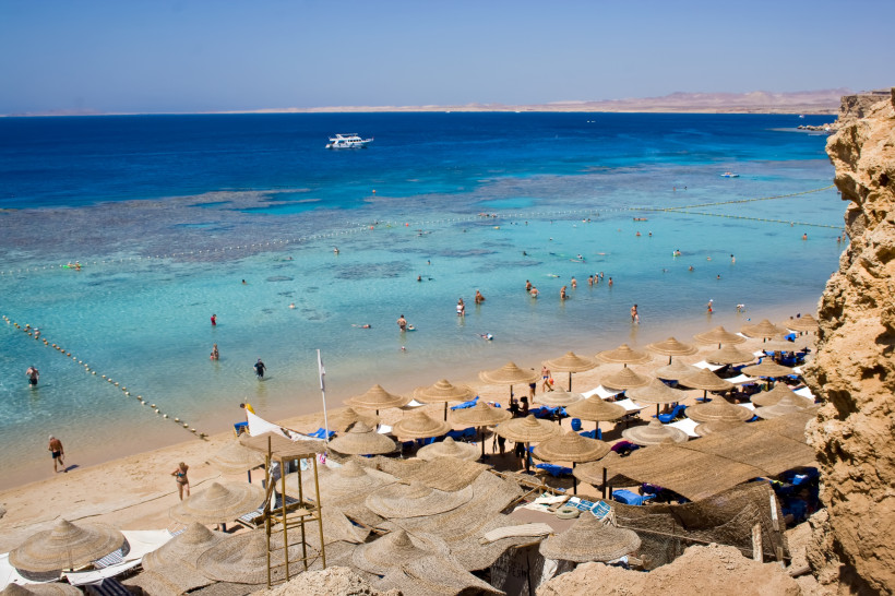 Frühling in Ägypten Leute sonnen sich und schwimmen im Meer, am Strand gibt es Strohschirme