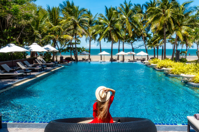 Thailand Resort mit Pool – Komfortabler Urlaub mit gutem Preis-Leistungs-Verhältnis Frau am Pool eines Strandresorts in Thailand, umgeben von Palmen und Meer – komfortable Unterkunft für Reisen mit starkem Preis-Leistungs-Verhältnis.