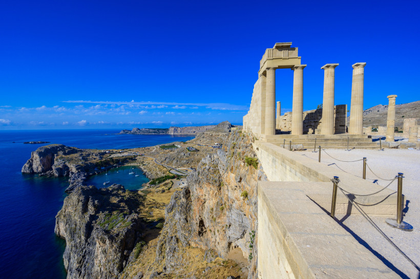 Antike Tempelruinen der Akropolis von Lindos auf Rhodos auf einer Klippe über dem tiefblauen Mittelmeer mit Blick auf Buchten und Küste.