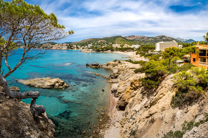 Blick über die Bucht von Playa La Romana mit türkisfarbenem Meer, Felsenküste und Hotels im Hintergrund