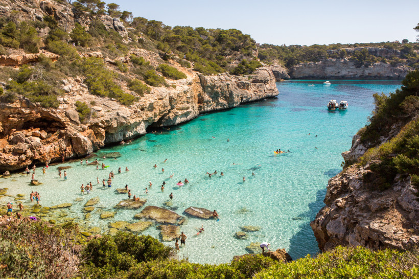 Cala des Moro: Felsbucht mit klarem, türkisfarbenem Wasser und Badegästen Blick auf die Cala des Moro mit türkisfarbenem Wasser, Felsklippen und Badenden