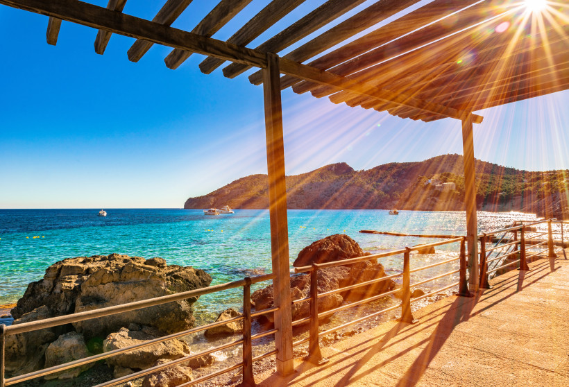 Holzüberdachte Promenade mit Blick auf die Bucht von Camp de Mar und das türkisfarbene Mittelmeer