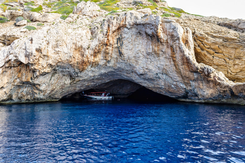 Felsgrotte Cave Cabrera mit Höhlenöffnung am Meer und Boot im Eingang