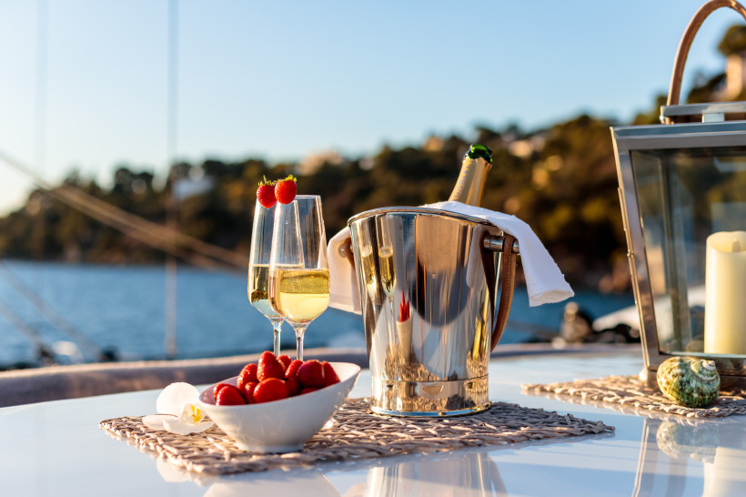 Romantischer Champagnermoment auf dem Meer – perfekter Luxus-Genuss Champagner, Gläser mit Erdbeeren und frische Früchte auf einem Boot mit Meerblick. Romantische Szene für Hochzeitsreise oder Luxusurlaub.