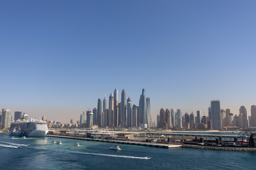 Kreuzfahrtschiff im Hafen von Dubai vor der Skyline mit Hochhäusern