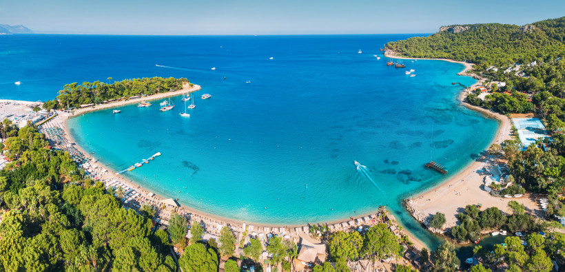 Traumhafte Bucht bei Kemer – Kristallklares Wasser, Yachten und grüne Küstenlandschaft Panoramablick auf eine türkisfarbene Bucht bei Kemer mit Yachten, feinem Strand, dichten Pinienwäldern und glasklarem Wasser der Türkischen Riviera.