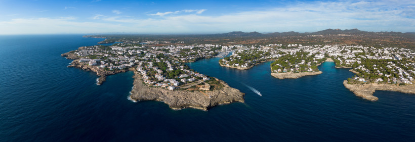 Weitwinkelaufnahme der zerklüfteten Küste von Cala d’Or mit mehreren kleinen Buchten und weißen Ferienanlagen