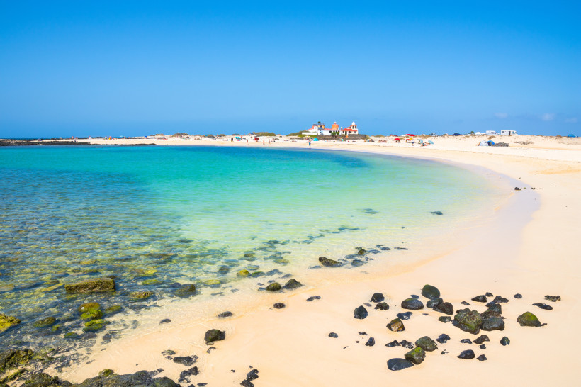 El Cotillo Lagunen – Türkisblaues Naturparadies im Norden Fuerteventuras Kristallklares, türkisfarbenes Wasser in den Lagunen von El Cotillo auf Fuerteventura, mit weißem Sandstrand und dunklen Lavasteinen im Vordergrund.