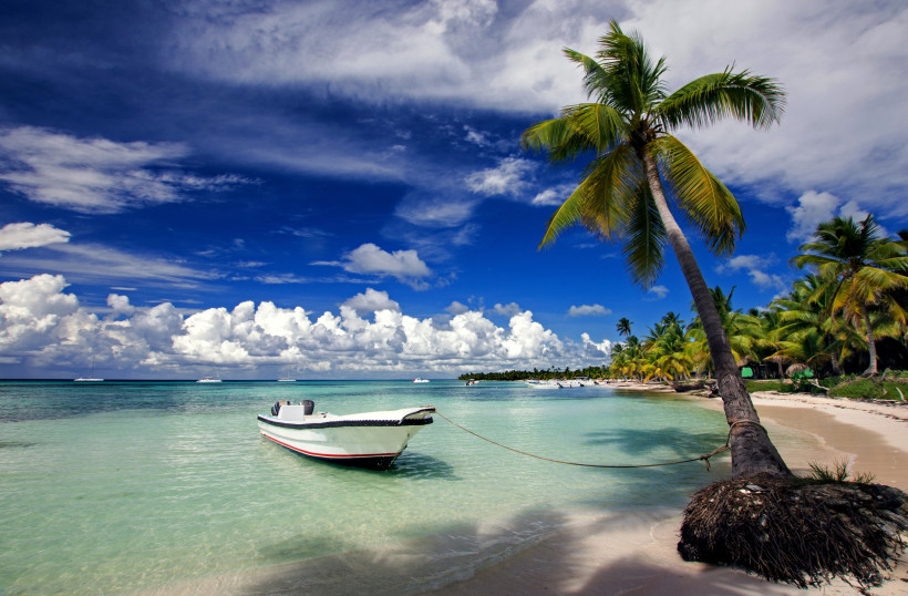 Dominikanische Republik Weißer Sandstrand mit türkisblauem Meer, Palmen und Boot an der Küste von Isla Saona, Dominikanische Republik