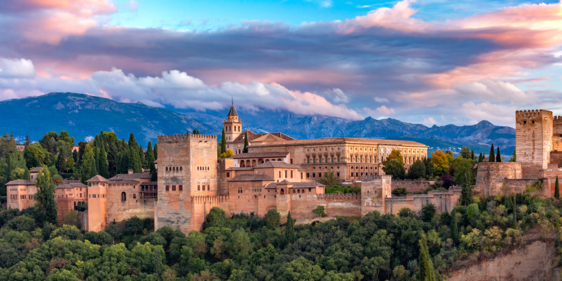 Blick auf den Palast- und Festungskomplex Alhambra in Granada vor Bergen und bewölktem Himmel
