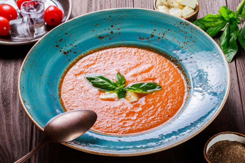Schale mit Gazpacho, garniert mit Basilikum und Olivenöl