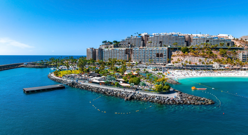 Blick auf Playa de Amadores und Hotelanlagen Luftaufnahme von Playa de Amadores auf Gran Canaria mit türkisblauem Wasser, hellen Sandstränden und modernen Hotelanlagen – ein beliebter Ort für Badeurlaub und Sonnenanbeter.