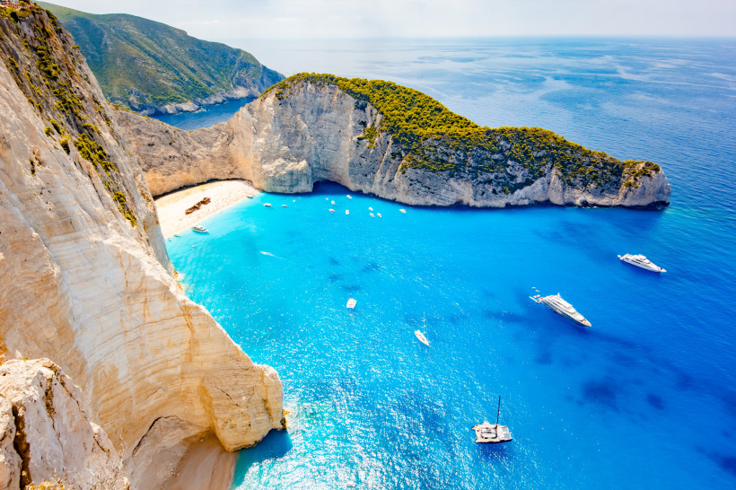 Bucht mit steilen Kalksteinklippen und türkisblauem Meer auf Zakynthos, mit Strand und Booten