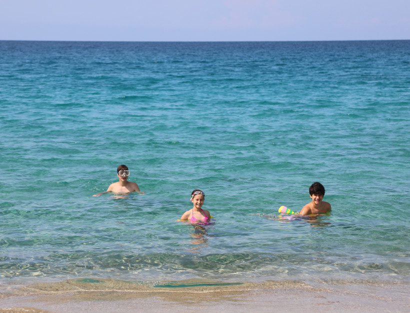 Drei Kinder im flachen Meerwasser am Strand von Playa d'en Bossa