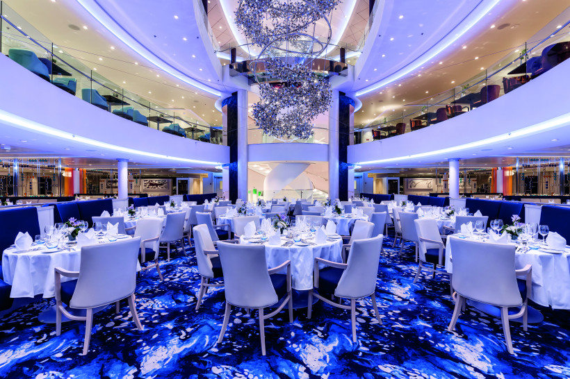 Atlantik-Klassik-Restaurant auf der Mein Schiff 6 mit gedeckten Tischen und großer Kronleuchterinstallation im Atrium