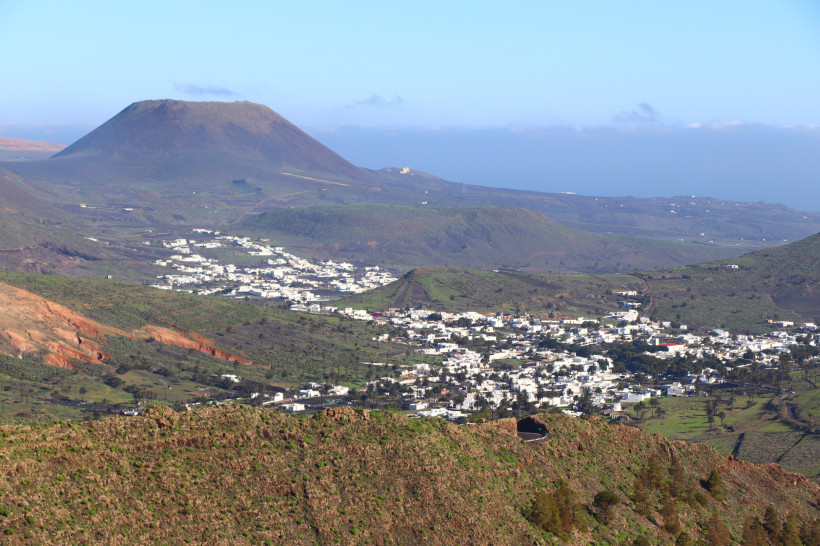 Panoramablick auf Haría und die Vulkanlandschaft im Norden Lanzarotes Panoramaaufnahme von Haría auf Lanzarote mit weißen Häusern, Bergen und vulkanischer Landschaft im Hintergrund.