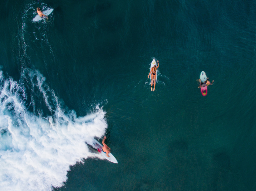 Canggu, Bali Surfer im türkisblauen Meer von Bali, während andere Surfer auf ihren Boards auf die nächste Welle warten