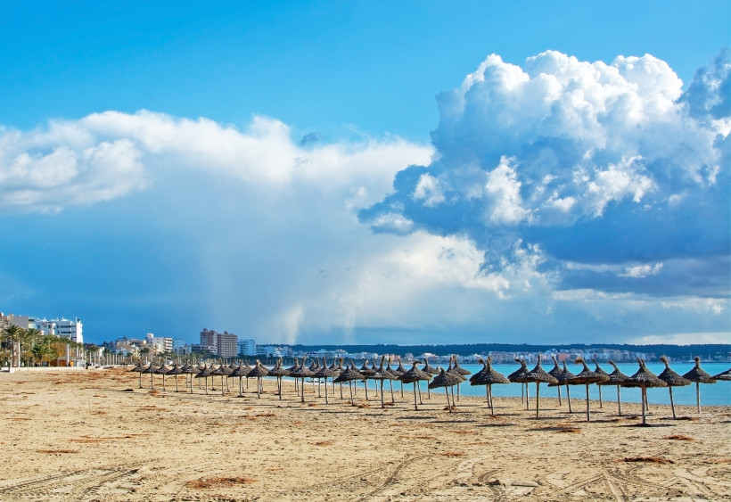 Sandstrand von Can Pastilla mit Sonnenschirmen und Blick Richtung Palma