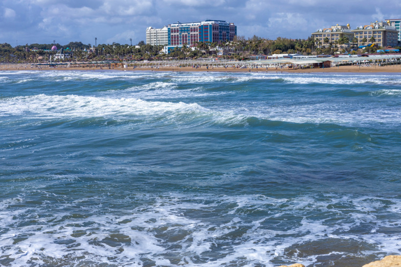 Blick auf den Strand von Evrenseki bei Side mit Wellen, Sandstrand und Hotels im Hintergrund