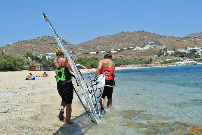 Mykonos - Kalafatis Zwei Windsurfer am Kalafatis Beach auf Mykonos tragen ihre Surfbretter ins türkisfarbene Meer