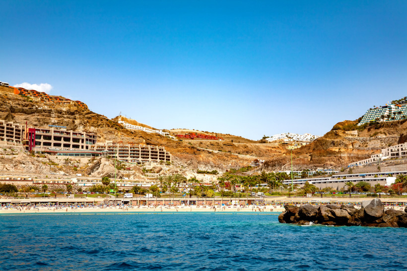 Blick auf die Playa de Amadores mit Sandstrand, türkisfarbenem Meer und Hotelanlagen am Hang
