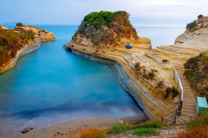 Felsige Küstenformationen am Canal d’Amour in Sidari, Korfu, bei Sonnenaufgang Canal d’Amour bei Sidari auf Korfu mit felsiger Küste und ruhigem, blauem Ionischen Meer bei Sonnenaufgang