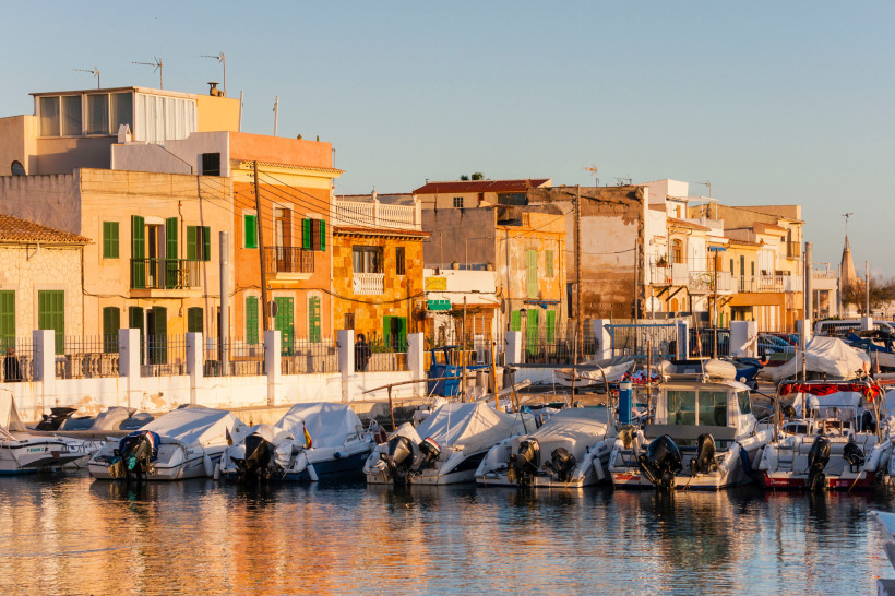 Kleiner Hafen von El Molinar mit Booten, bunten Häusern und ruhigem Wasser