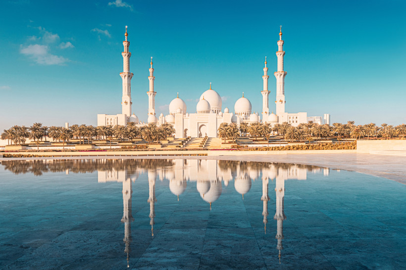 Sheikh Zayed Moschee in Abu Dhabi mit Spiegelung im Wasser bei blauem Himmel