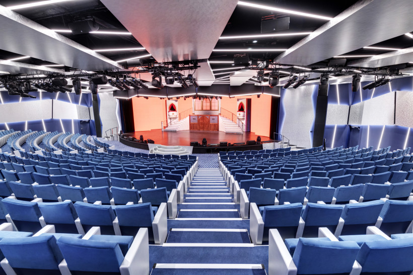 MSC Grandiosa – Théâtre La Comédie, Zuschauerraum mit Bühne Theater Théâtre La Comédie auf der MSC Grandiosa mit Reihen blauer Sitzplätze und Blick auf die Bühne