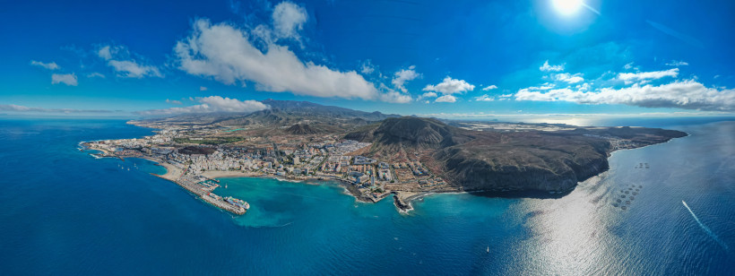 Atemberaubender Panoramablick über den Süden Teneriffas Panoramaaufnahme des Südens von Teneriffa mit Playa de las Américas und Costa Adeje, hellen Sandstränden, blauem Meer und Vulkanlandschaft im Hintergrund unter blauem Himmel.