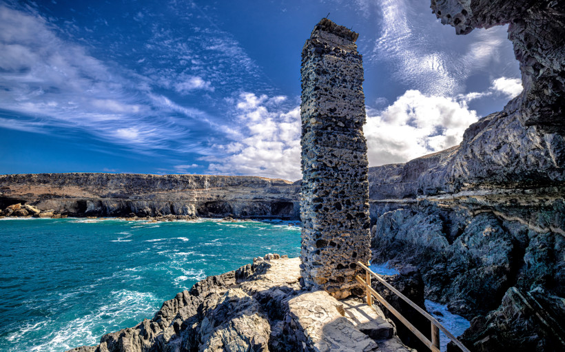 Cuevas de Ajuy: Dramatische Klippen und Felsformationen an der Westküste Fuerteventuras Steinerner Felssteg und markante Felsformationen an den Klippen der Ajuy-Höhlen auf Fuerteventura mit Blick auf das Meer.