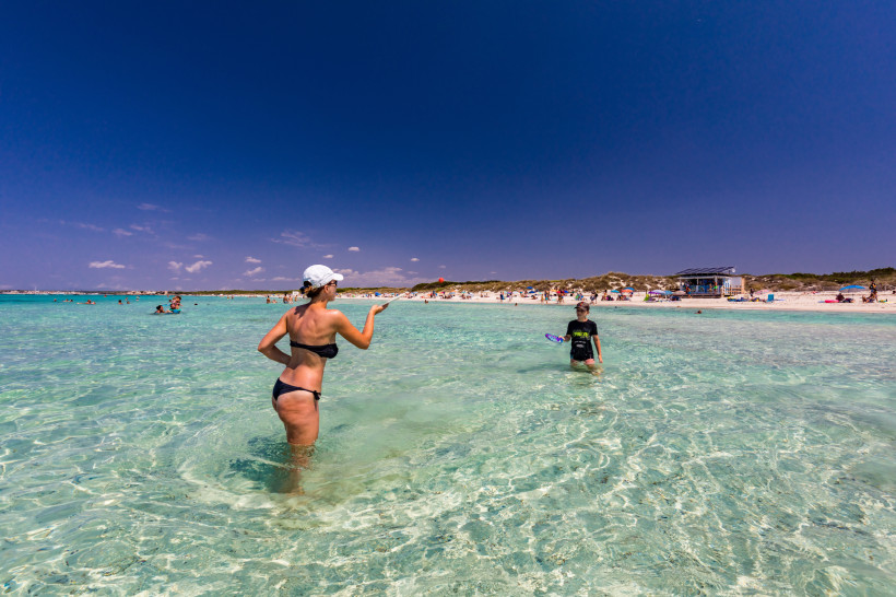 Personen im flachen, klaren Meerwasser am Strand von Colonia de Sant Jordi