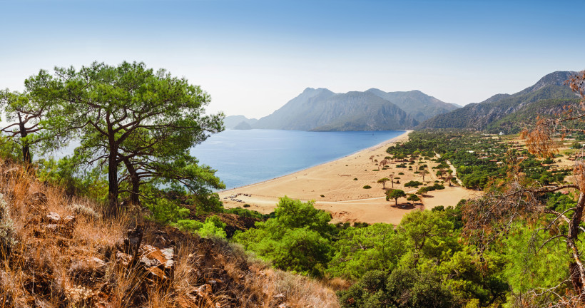 Naturstrand bei Kemer an der Türkischen Riviera mit Pinienwäldern, Sandstrand, türkisblauem Meer und dem Taurusgebirge im Hintergrund