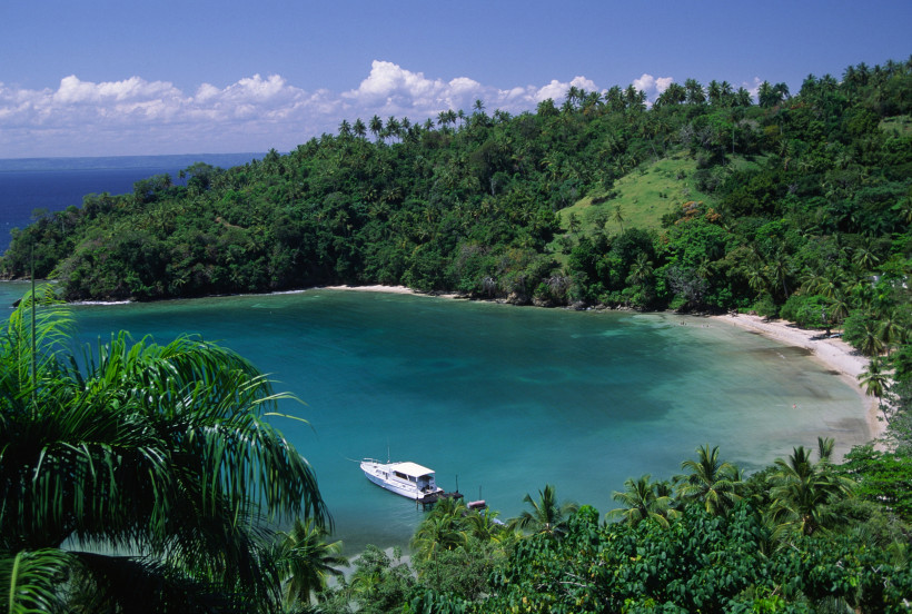 Samaná-Halbinsel, Dominikanische Republika Idyllische Bucht bei Samaná in der Dominikanischen Republik mit türkisblauem Wasser, üppig grünen Hügeln und einem Boot am Ufer