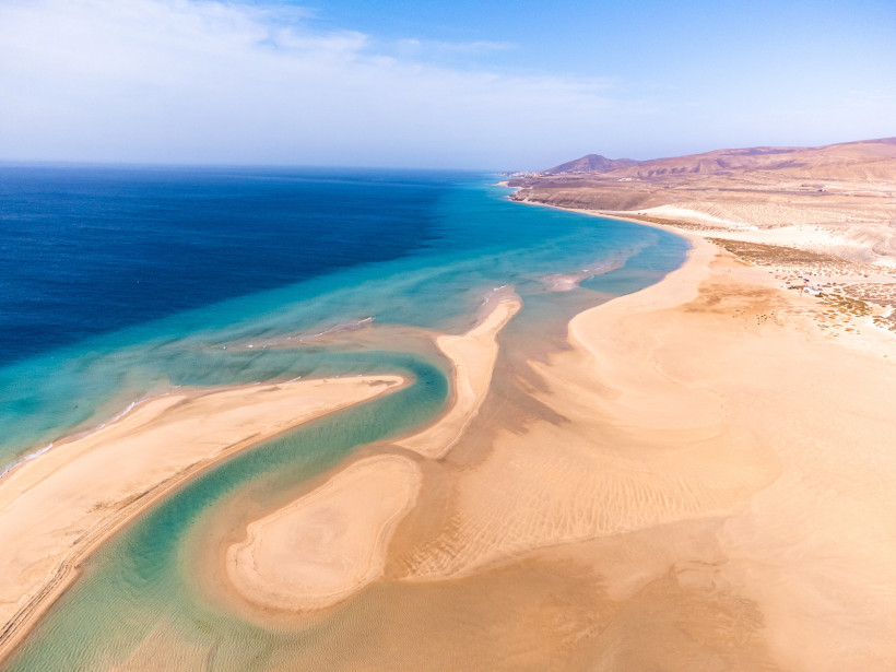 Luftaufnahme einer Lagune auf Fuerteventura mit Sandbänken, türkisfarbenem Wasser und weitem Sandstrand