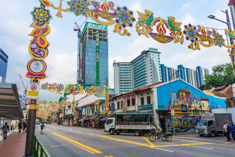 Straßenszene in Little India, Singapur Belebte Straße in Little India, Singapur, mit bunter Festdekoration, Geschäften und modernen Hochhäusern im Hintergrund