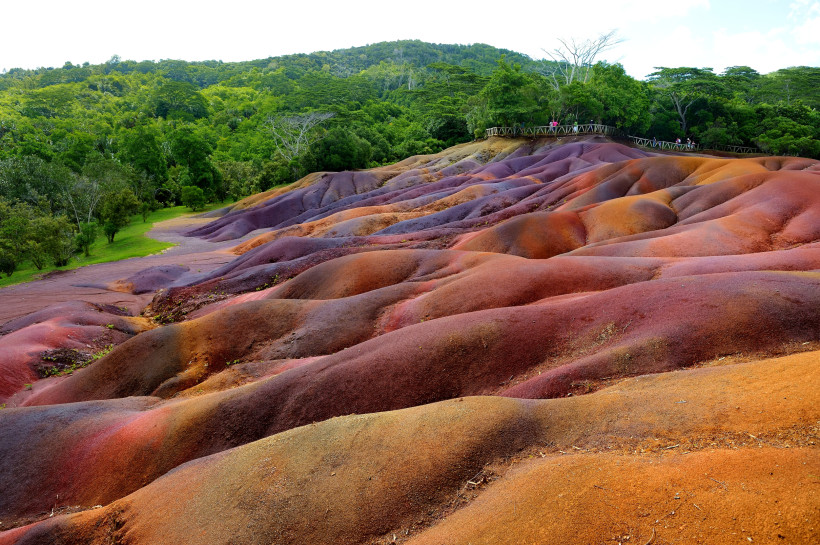 Die Siebenfarbige Erde in Chamarel, Mauritius – wellige Dünenlandschaft in Rot- und Lilatönen, umgeben von tropischem Grün