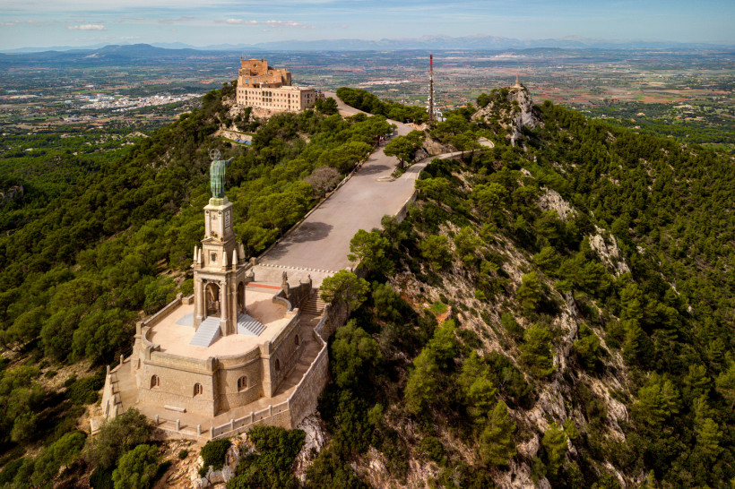 Luftaufnahme des Santuari de Sant Salvador bei Artà auf Mallorca, Wallfahrtskirche auf einem Hügel mit weitem Blick über Landschaft und Küste