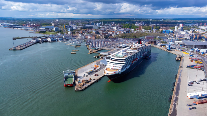 Luftaufnahme des Hafens von Southampton mit Kreuzfahrtschiff am Terminal und Stadt im Hintergrund