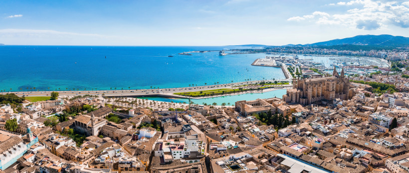 Mallorca - Palma de Mallorca Panoramablick auf Palma de Mallorca mit Blick auf die Altstadt und die berühmte Kathedrale La Seu. Im Vordergrund die alten, sandfarbenen Häuser mit ihren typischen Dächern. Dahinter erhebt sich die gotische Kathedrale, flankiert von der Hafenpromenade mi