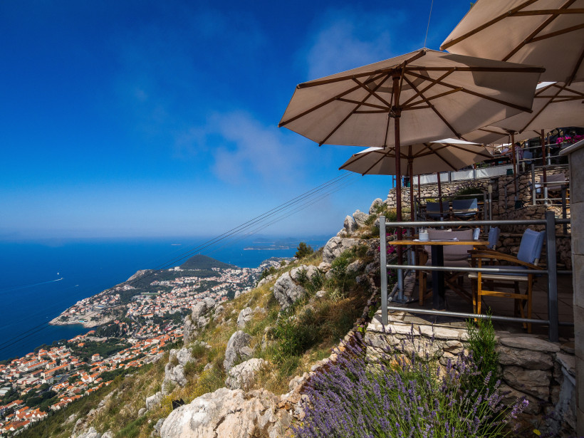 Blick von einer Terrasse mit Sonnenschirmen auf Dubrovnik und die Adriaküste während eines Kreuzfahrtstopps