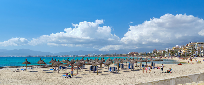 Strand in El Arenal mit Strohschirmen, Liegen und Blick auf das Meer