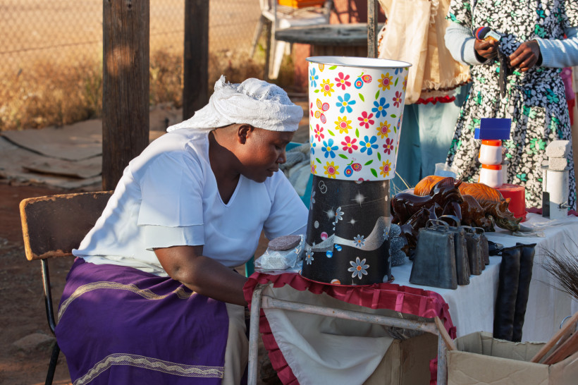 Südafrika Nahaufnahme eines Marktstandes mit vielen farbenfrohen, handgefertigten Armbändern aus Perlen in traditionellen Mustern und Farben. Im Vordergrund sind auch Schnitzarmbänder zu sehen.