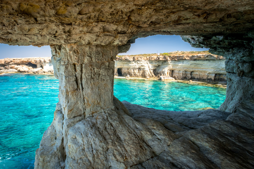 Blick aus einer Meeresgrotte bei Kap Greco auf Zypern auf türkisblaues Wasser und helle Kalkklippen der Sea Caves.