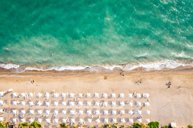 Strandurlaub in Belek – Türkises Mittelmeer und gepflegte Strandabschnitte mit Sonnensegeln Draufsicht auf den Strand von Belek mit türkisem Meer, sanften Wellen und zahlreichen weißen Sonnensegeln entlang des feinen Sandstrands