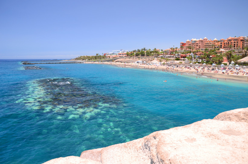 Blick auf die Playa del Duque auf Teneriffa mit Sandstrand, türkisblauem Meer und Hotels im Hintergrund