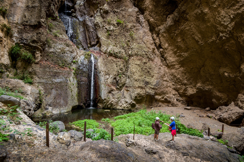 Barranco del Infierno: Wasserfall in einer felsigen Schlucht mit Becken Wasserfall in der Schlucht Barranco del Infierno mit kleinem Becken und zwei Wanderern im Vordergrund