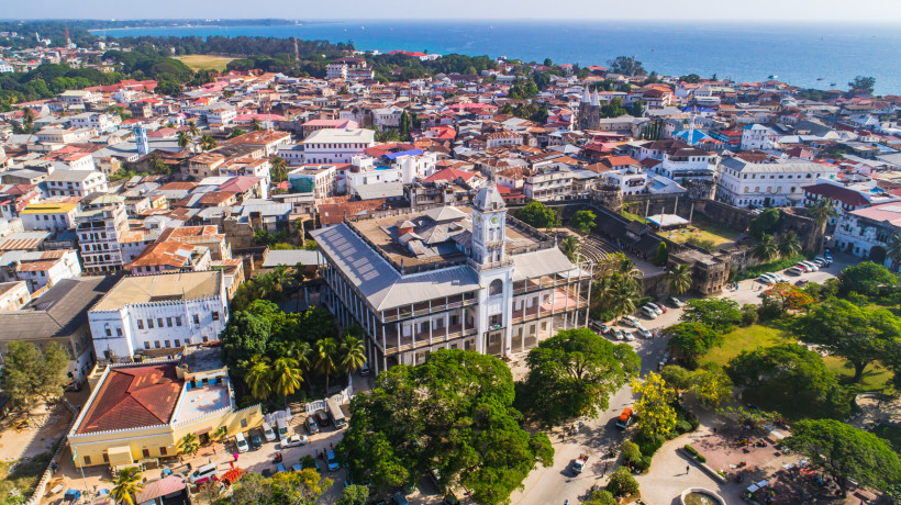 Sansibar Stone Town auf Sansibar aus der Luft: House of Wonders mit Uhrturm, daneben das Old Fort, Dächer der Altstadt und Indischer Ozean im Hintergrund