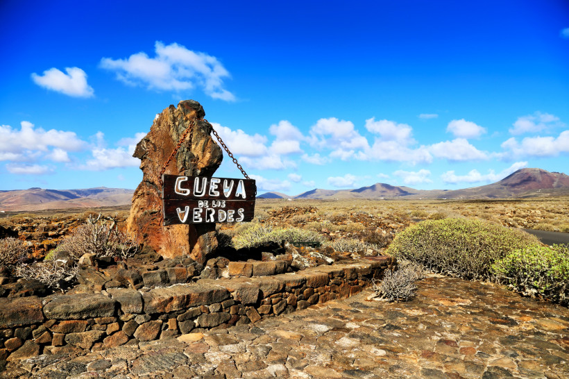 Cueva de los Verdes – Faszinierende Lavahöhle auf Lanzarote für spannende Vulkan-Touren Eingang zur Cueva de los Verdes auf Lanzarote mit Lavagestein und blauem Himmel