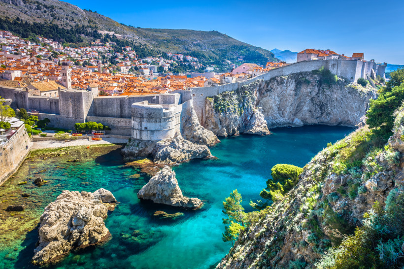 Blick auf die Altstadt von Dubrovnik mit massiven Stadtmauern am türkisblauen Meer